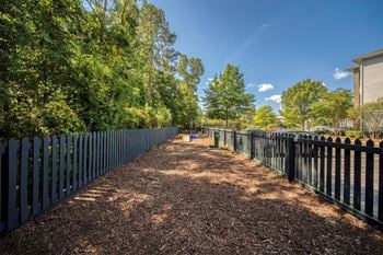 A long, narrow pathway flanked by trees and fences